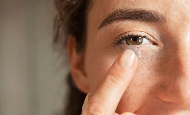 Man holding a contact lens up near his eye