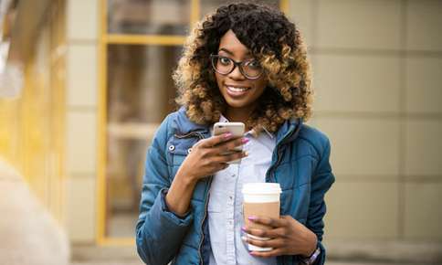 Woman holding her phone and a cup of coffee