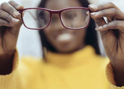 Woman with blurry vision holding up glasses