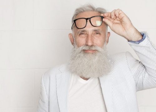 Older man with hyperopia lifting up his glasses